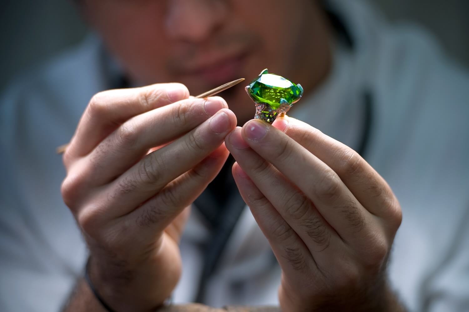 Picture of a man examining a green colored gems