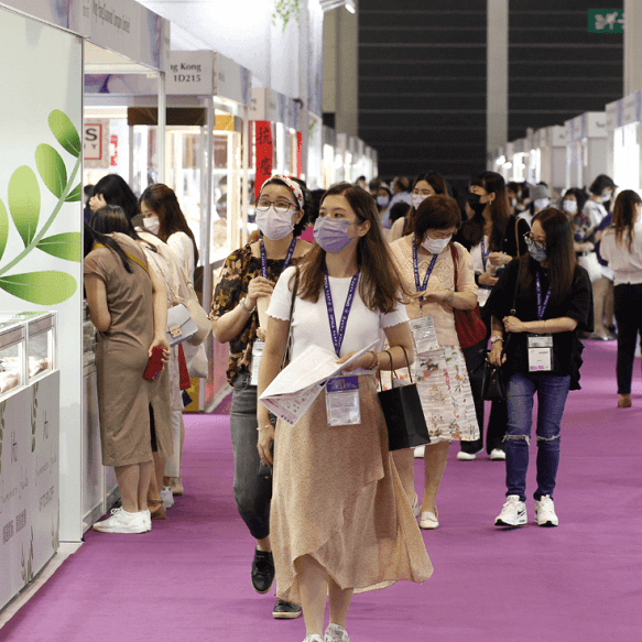 Picture of a masked woman walking in the isle of a gem and jewellery show